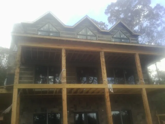 Dormers and porch framing on a large log home under construction — Roof Coating work by our crew in Dallas Center