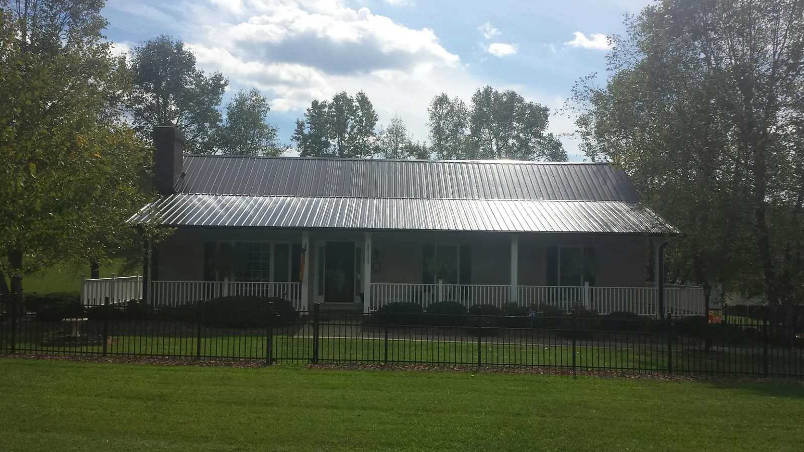 Gray metal roof on a brick ranch with a full width front porch — Gutter Guard Installation work by our crew in Dallas Center