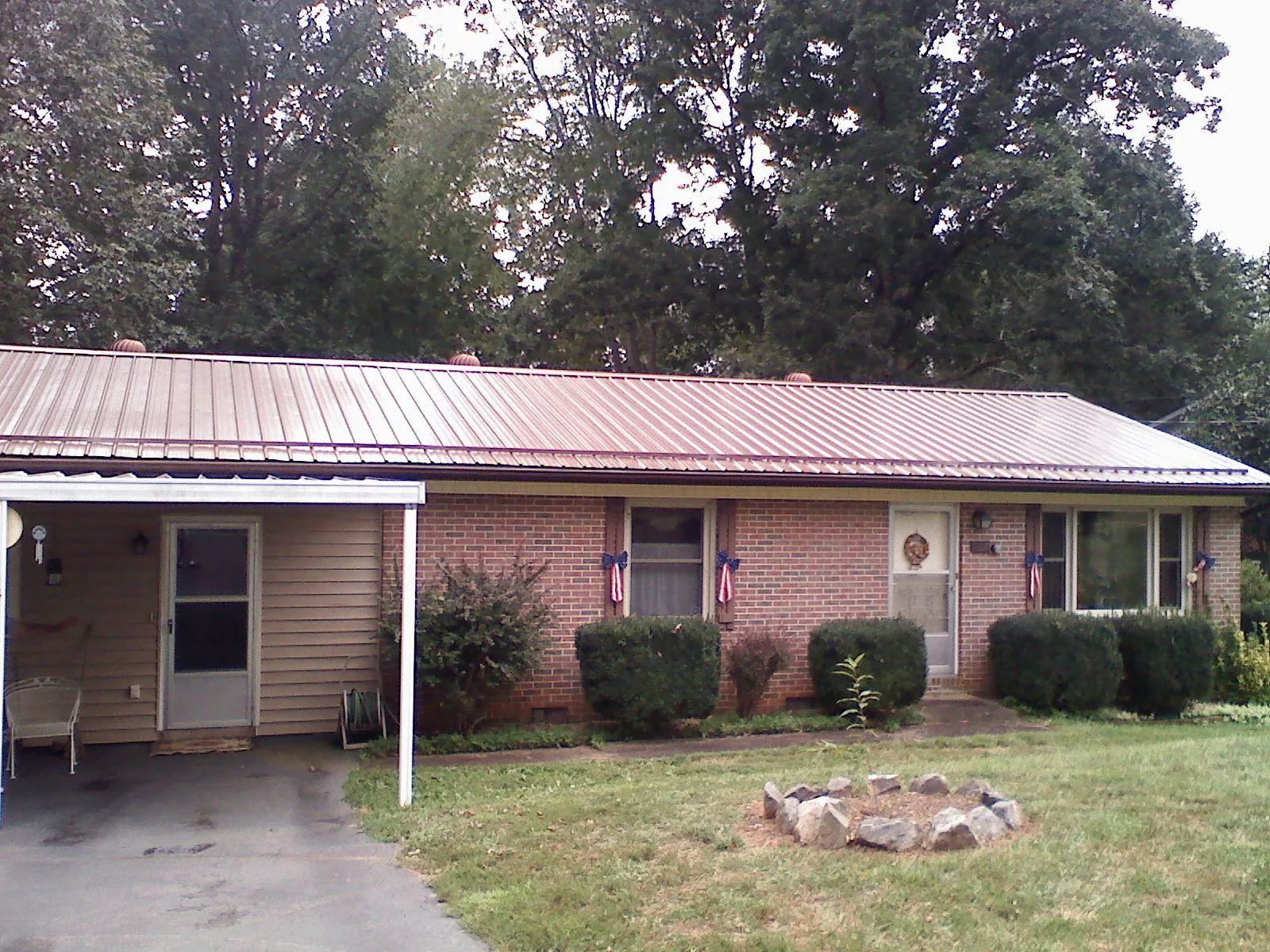 Bronze metal roof and carport on a brick ranch home — Roof Repair work by our crew in Dallas Center